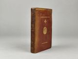 a brown book with a gold emblem sitting on top of a white surface