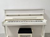 une photo d'un piano blanc posé à côté d'un banc