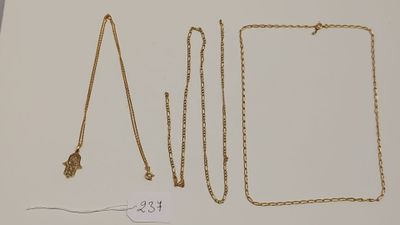 trois colliers en or et un collier avec une chaîne posés sur une table