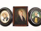 three framed portraits of two men and a woman on a wall