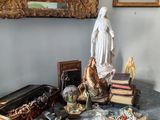 une statue de Jésus assis sur une table, à côté d'une pile de livres