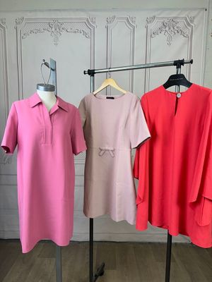 three women ' s dresses on a rack in a white room