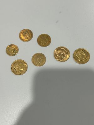 some gold coins sitting on top of a table next to a shadow of a person