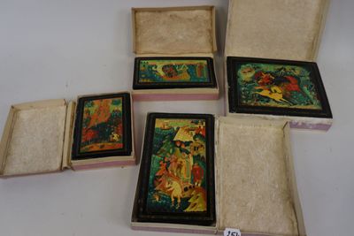 quatre petites boîtes en bois ornées de peintures, posées sur une table
