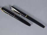 two black and gold fountain pens sitting next to each other