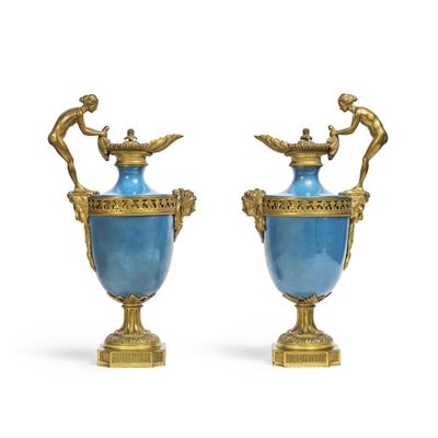 paire de vases bleus et dorés ornés de figurines sur des socles