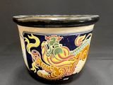 un pot noir et jaune orné d'un motif représentant un dragon