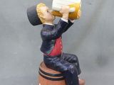 figurine représentant un homme assis sur un tonneau, en train de boire à la bouteille