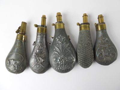 five antique silver and gold perfume bottles lined up on a white surface