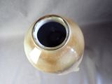 a brown vase with a black lid sitting on a white surface