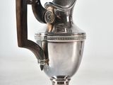a silver pitcher with a wooden handle on a table