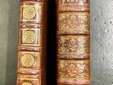 two old books are sitting on a table next to each other