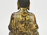 a gold statue of a buddha sitting on a white surface