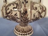 a white vase with brown designs on it on a blue table