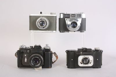 three old cameras sitting side by side on a white surface
