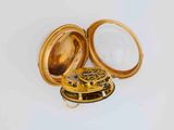 a gold pocket watch sitting on a white surface