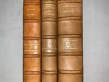 three old leather books sitting on top of each other on a table