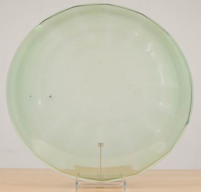 an image of a green glass plate on a stand on a wooden table