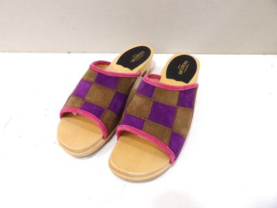 une paire de chaussons violets et marron posés sur une surface blanche