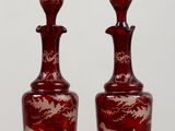two red glass vases sitting on top of a wooden table