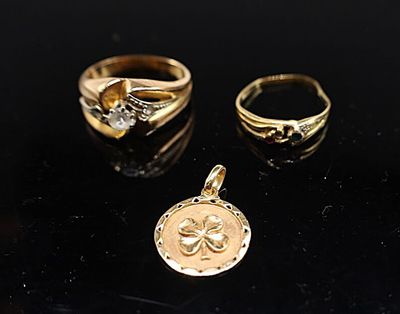 trois bagues en or et un pendentif sur un fond noir