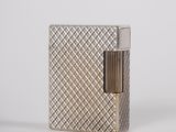 a silver lighter sitting on top of a table next to a white wall