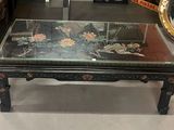 une table basse avec un plateau en verre et un miroir accroché au mur