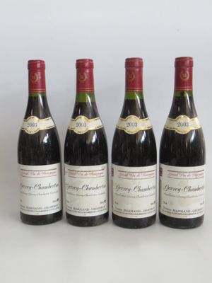 quatre bouteilles de vin sont alignées sur une surface blanche