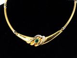 a gold necklace with a green stone in the center