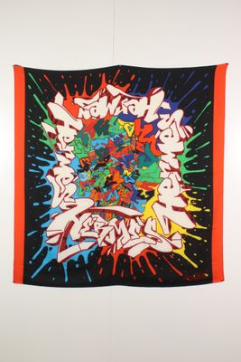 a wall hanging with graffiti on it in a room