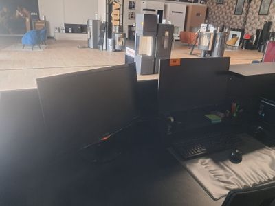 deux écrans d'ordinateur posés sur un bureau dans une pièce