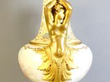 a gold and white vase with a woman on it