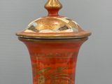 a red and white vase with a gold lid
