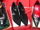 trois paires de chaussures noires dans une boîte posée sur un tissu rouge