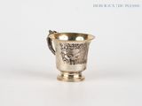 a silver cup with a handle on a white surface