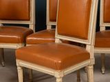 four chairs with leather upholstered backs and a wooden frame