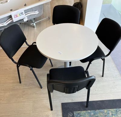 une table blanche et quatre chaises noires dans une pièce