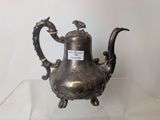 a silver tea pot on display on a glass table