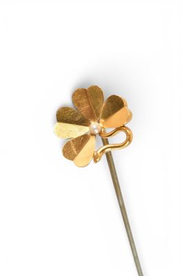 a gold flower on a stick with a pearl in the middle