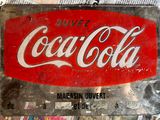 a coca cola sign sitting on top of a pile of newspapers