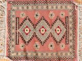 un vieux tapis à franges posé sur un parquet, près d'un mur