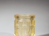 a close up of a yellow glass cup on a white surface