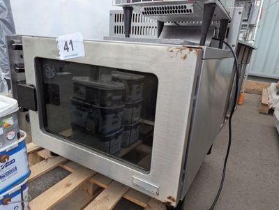 un micro-ondes argenté posé sur une palette dans un entrepôt