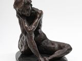 a bronze statue of a woman sitting on a black base