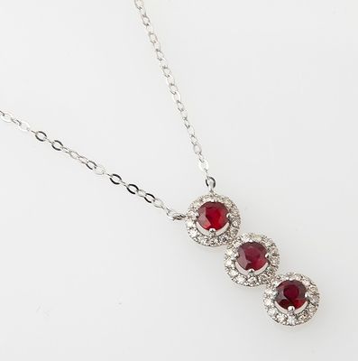 a close up of a necklace with three red stones on it