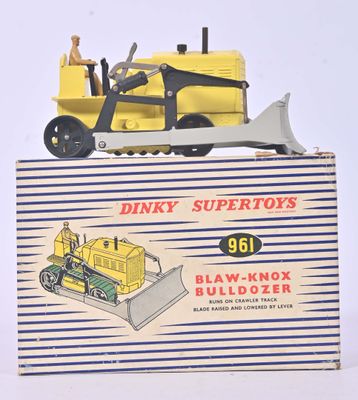un petit bulldozer jaune en plastique posé sur une boîte