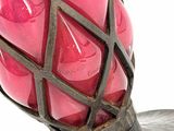 a pink vase with a metal cage on it
