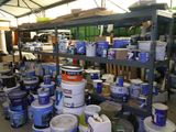 de nombreux seaux de peinture posés sur une étagère dans un entrepôt