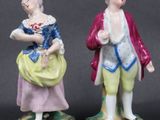 two figurines of a man and a woman standing next to each other