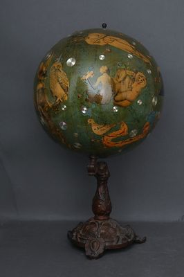 un globe vert et doré posé sur un socle en bois